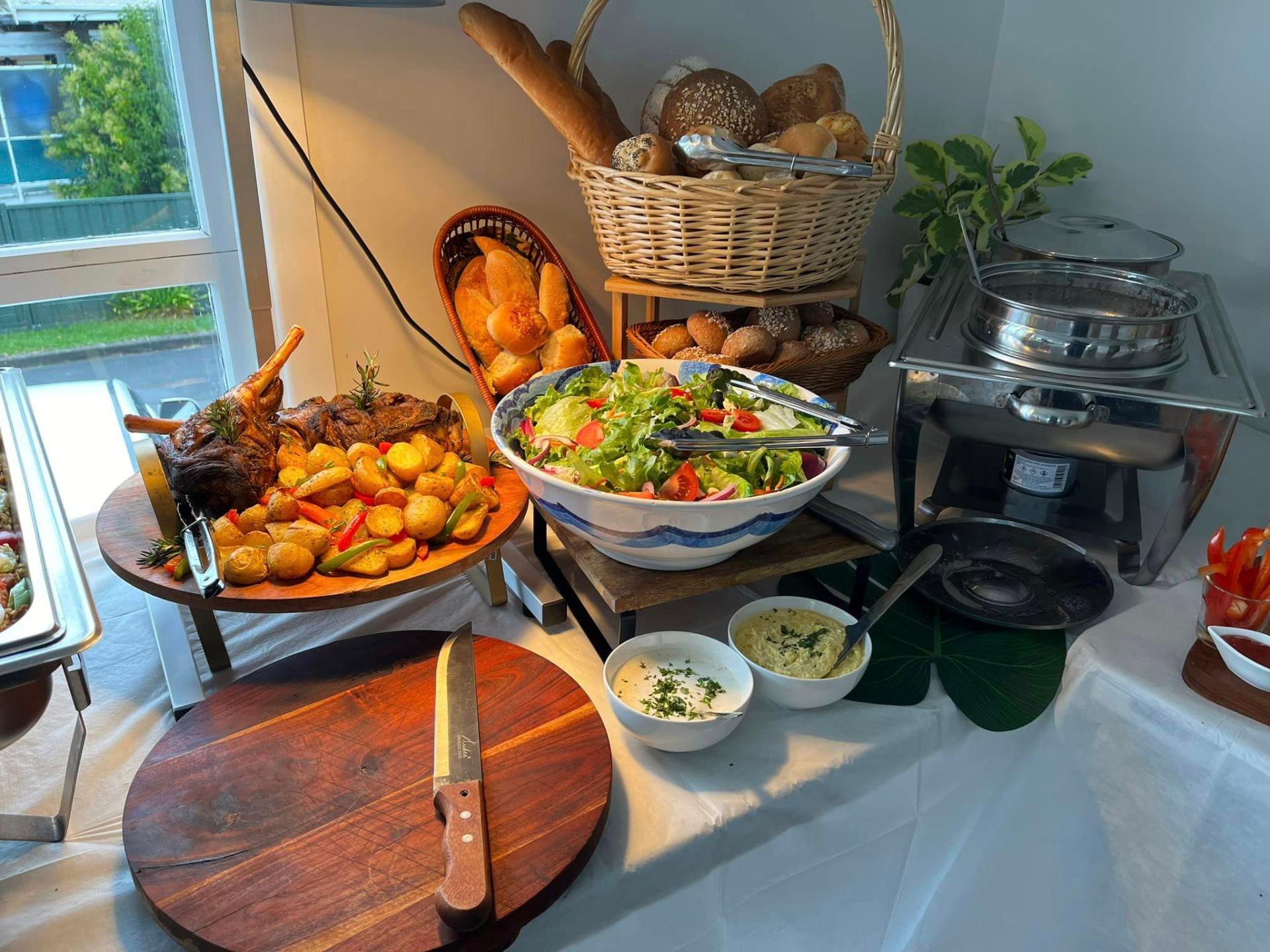 Roast lamb, salad and fresh bread buffet spread