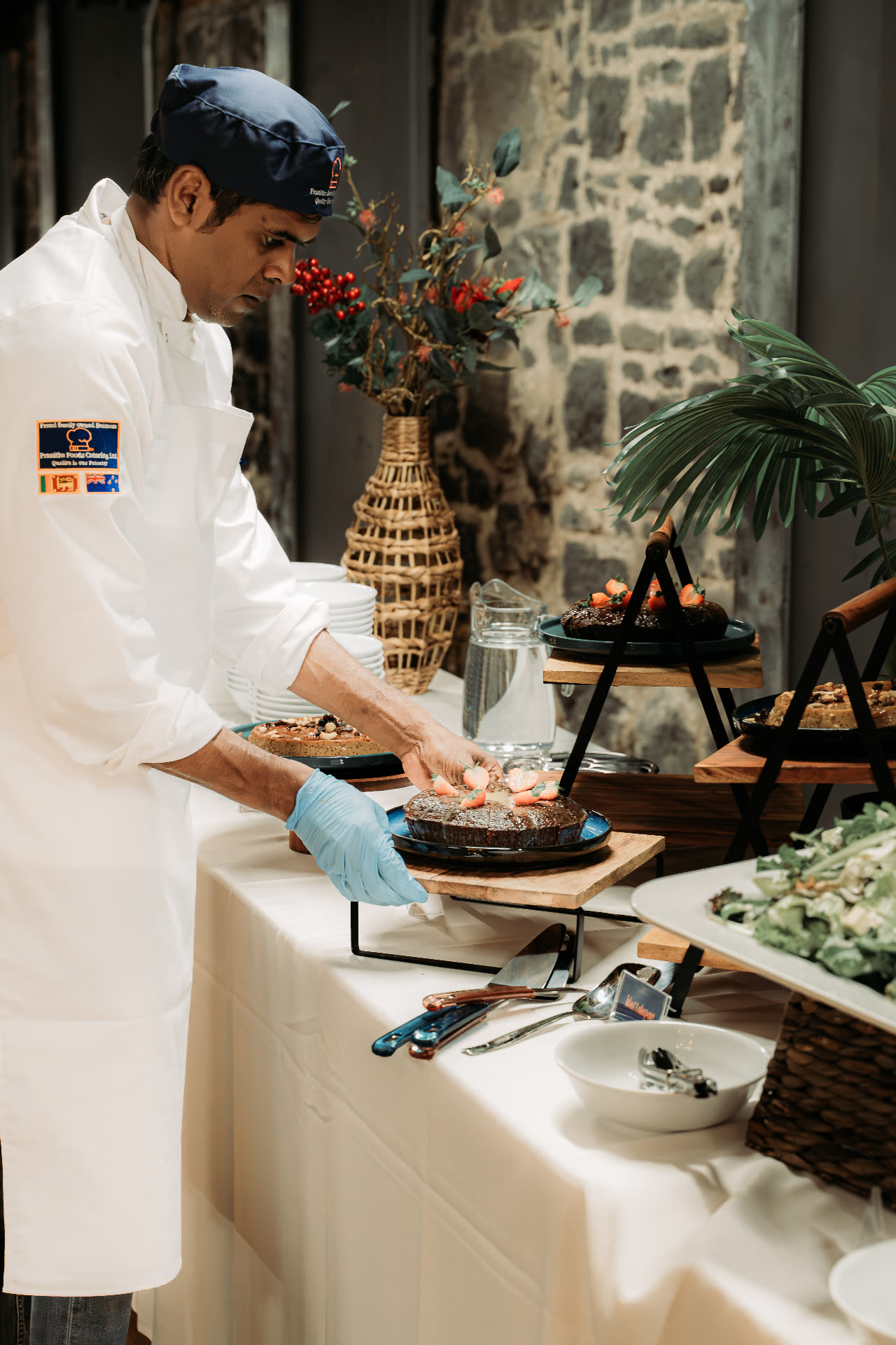 Chef plating dessert cakes at a Pranitha Foods buffet